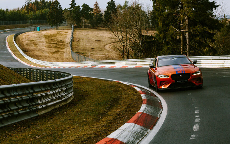Interview with racing driver Célia Martin Orange-blue Jaguar in a bend at the Nürburgring