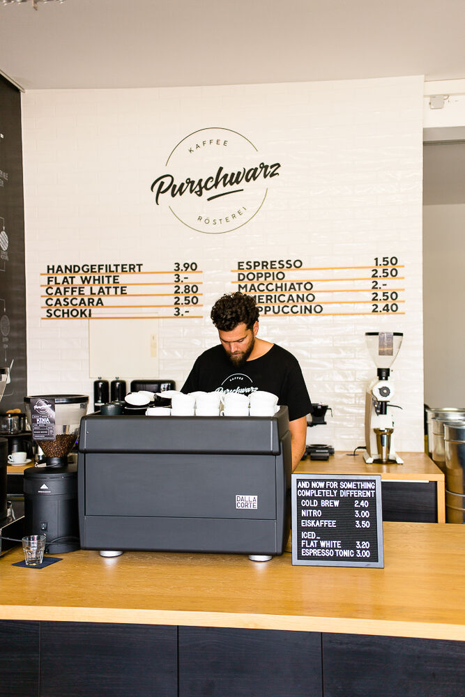 Portrait of the coffee manufacturer Purschwarz Alexander Gourgius stands at the counter of his coffee shop and prepares a cup of coffee