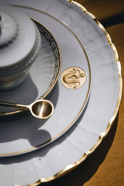 Host without stress: 7 golden rules for a dinner with friends Detail view of KPM porcelain with golden relief