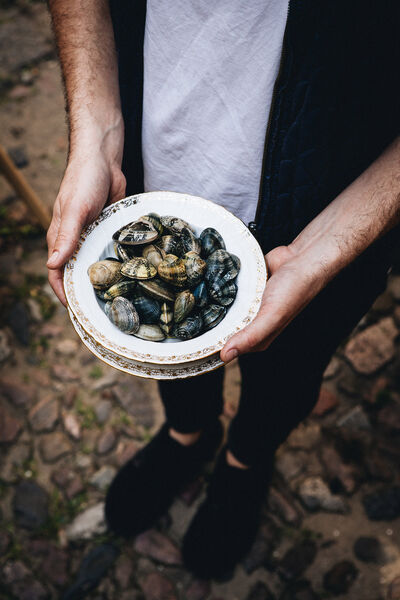 Host without stress: 7 golden rules for a dinner with friends Man holds a plate of mussels in his hand