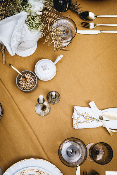 Host without stress: 7 golden rules for a dinner with friends View of the laid table from above with glasses, silverware, candles and a small bowl with pine nuts