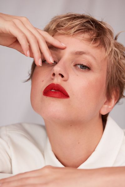 LUDWIG BECK Beauty: Cover shoot for the spring/summer 2020 issue Young woman in white jeans jacket wearing makeup and red lipstick against white background