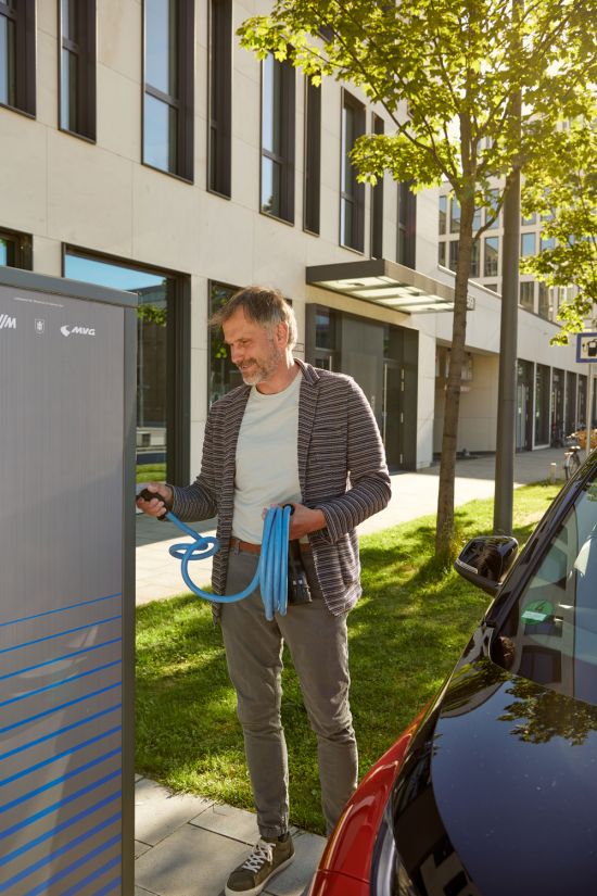 E-Mobility: Stadtwerke München creates charging solutions for electric vehicles Man stands in front of a charging station for electric vehicles with a cable in his hand