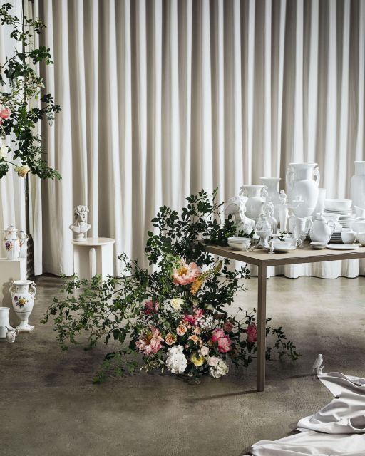 Snack de luxe: Scandinavian delicacies served on royal porcelain from KPM Flower bouquet in front of table laid out with white porcelain tablewares and beige curtain