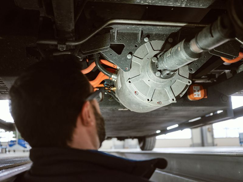 Company profile: Quantron AG from Augsburg, Germany Mechanic inspects the underbody of a vehicle