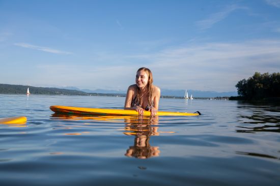E-boating on Lake Ammersee for SeeMagazin 2021 Young woman leaning on SUP board in the water