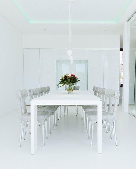Interior photo of a minimalistically furnished dining room with white walls, floor and furniture