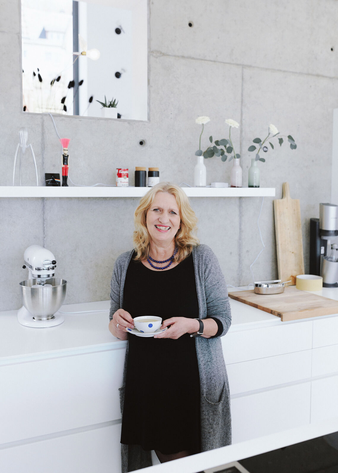 ORA Magazine: Behind-the-scenes at the homestory in Siegen Middle-aged blonde woman stands in modern kitchen and holds a cup in her hand