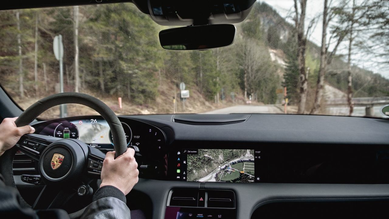 Driver's perspective from the cockpit of a Porsche Taycan 4 while driving on a mountain road.