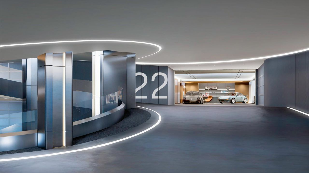View of a modern, illuminated underground parking garage in Bangkok with two classic Porsches.